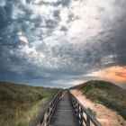 Boardwalk through grassy dune landscape on Sylt island at sunset