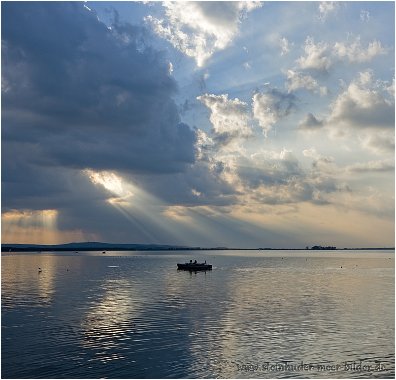 Boot als Silhouette auf dem Steinhuder Meer mit Sonnenstrahl und dramatischem Wolkenhimmel