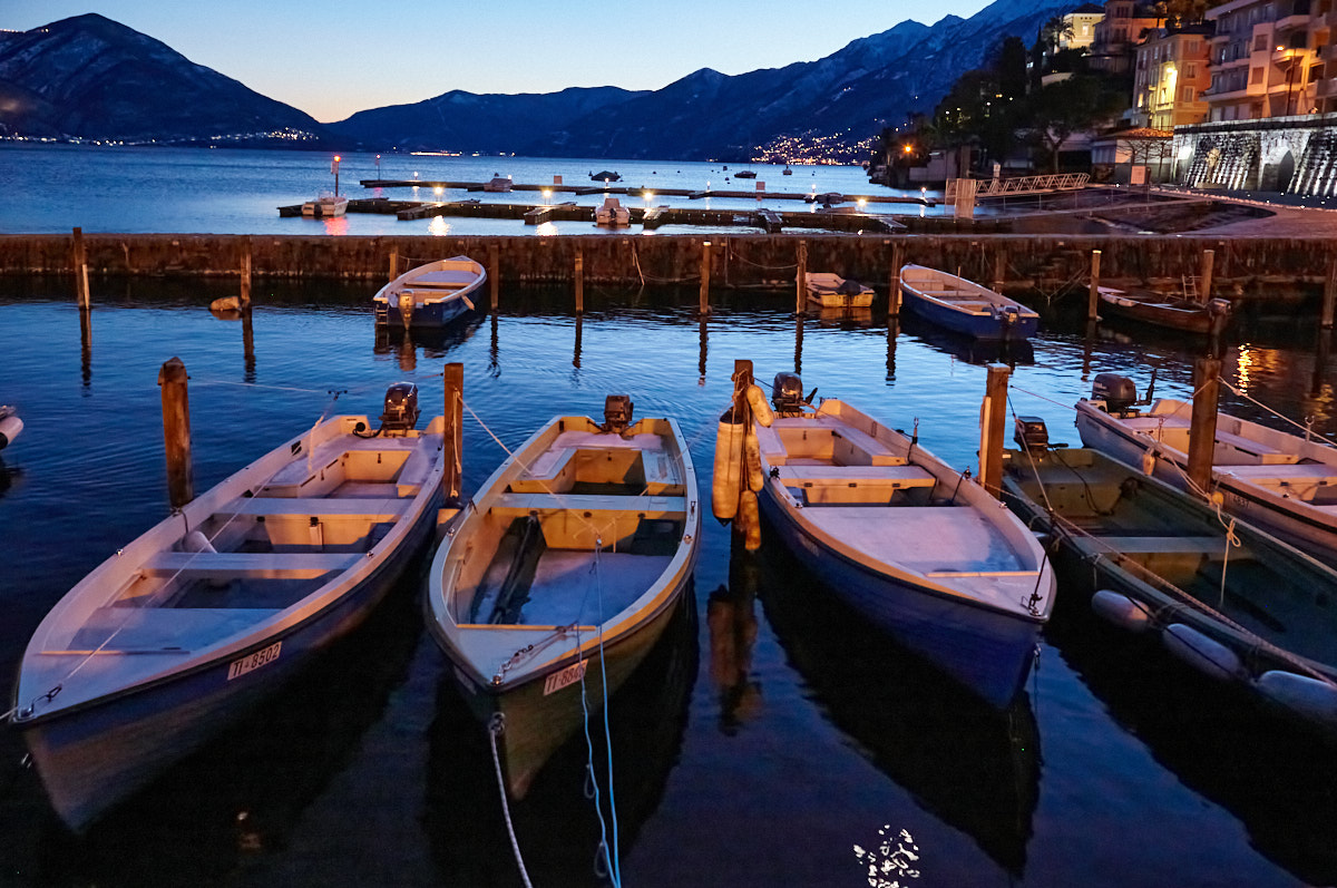 Boote am Lago Maggiore in der Bucht von Ascona (Kanton Tessin, Schweiz) zur blauen Stunde