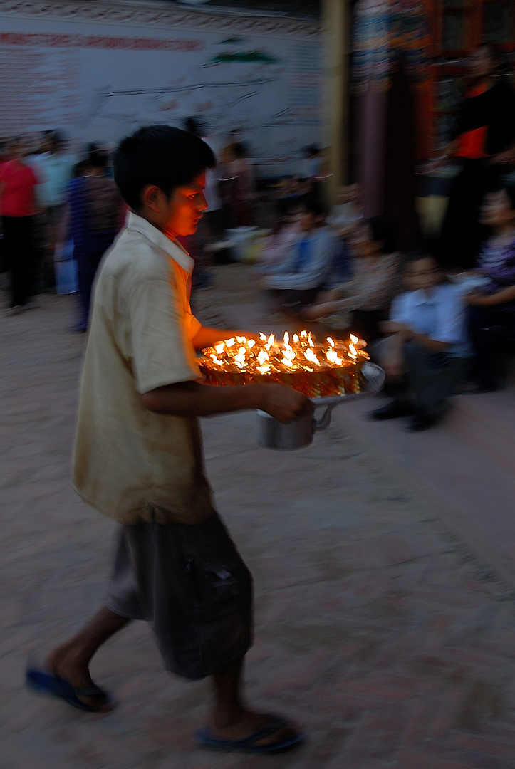 Boy brings new lighted butter lamps to the Gompa