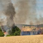 Brennender Mähdrescher verursacht Brand auf abgeerntetem Getreidefeld.