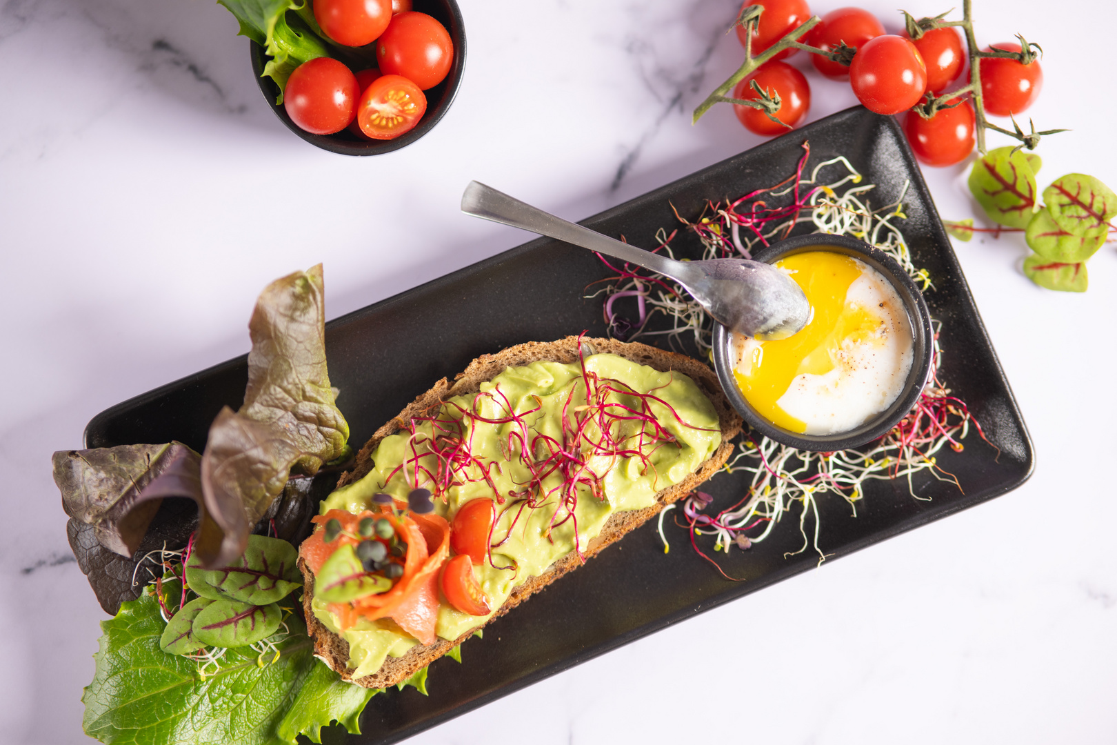 Brot, Avocado, Paradeiser und pochiertes Ei