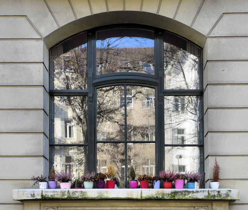 Bunte Töpfe vor spiegelndem Fenster