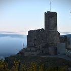 Burg mit Nebel im Hintergrund bei Sonnenaufgang