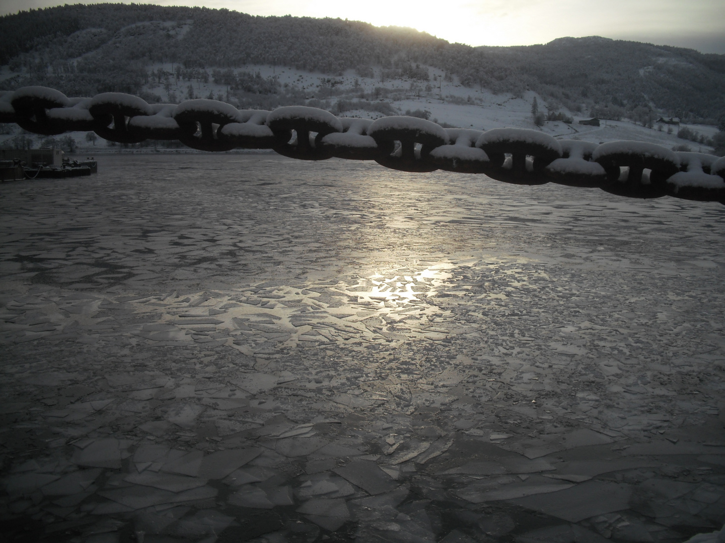 Catena innevata al tramonto sul fiordo ghiacciato.