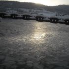 Catena innevata al tramonto sul fiordo ghiacciato.