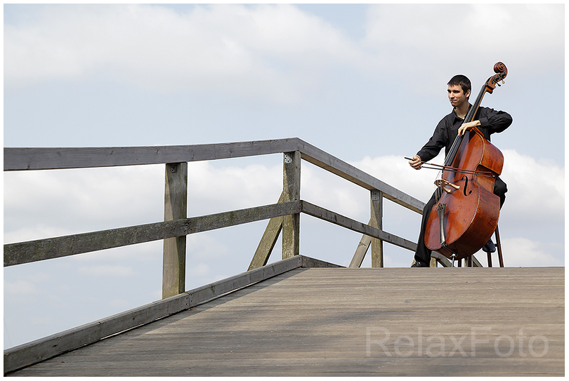 "Cello-Solo Open-Air" - Junger Mann spielt Cello auf Holzbrücke