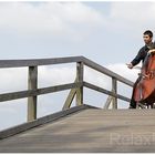 "Cello-Solo Open-Air" - Junger Mann spielt Cello auf Holzbrücke