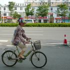 Chinesische Radlerin mit landesüblichem Sonnenschutz