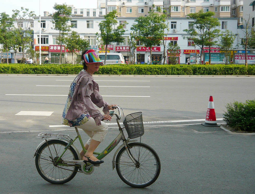 Chinesische Radlerin mit landesüblichem Sonnenschutz