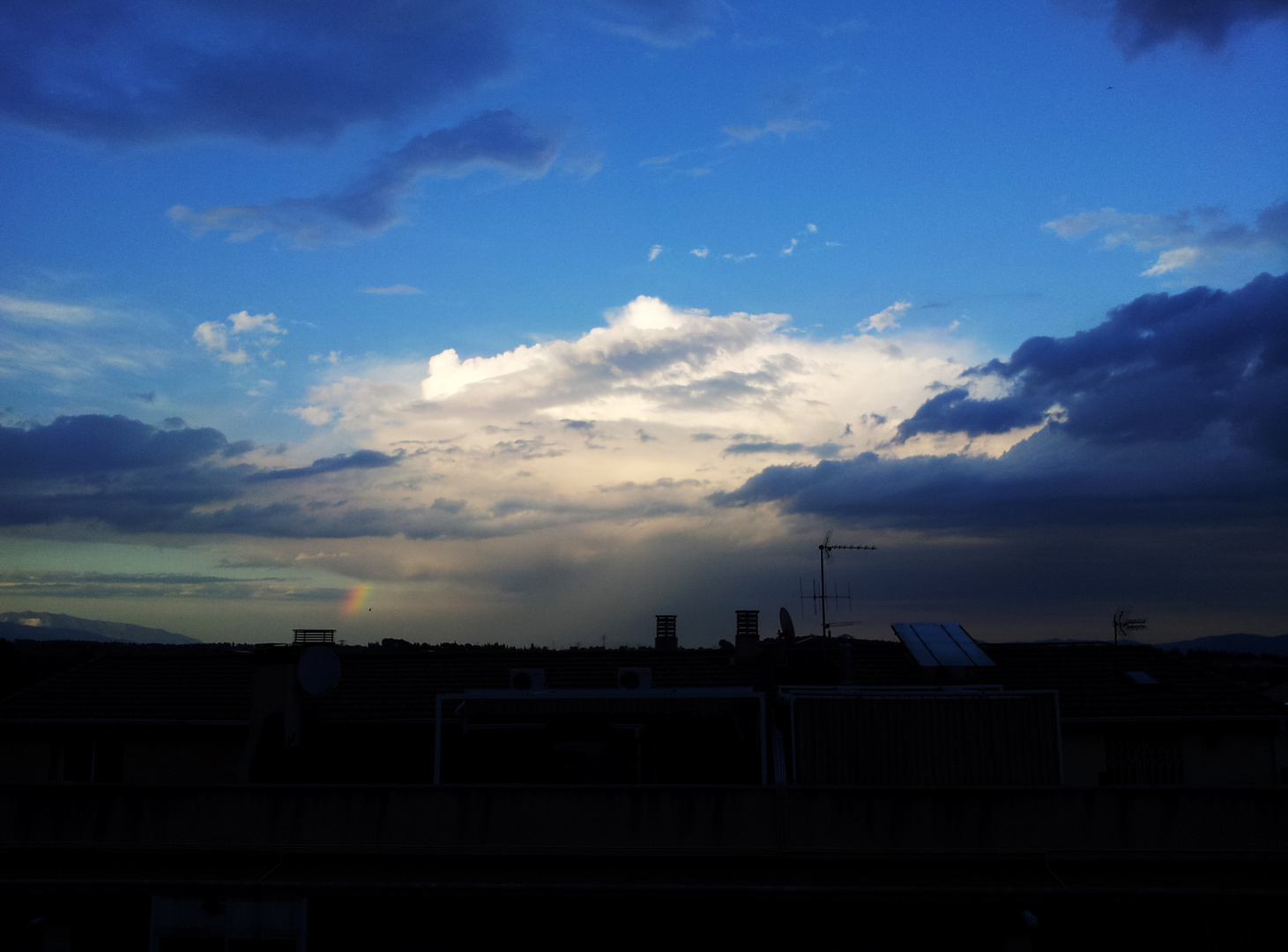 Cielo azul con un pequeño arco iris al fondo