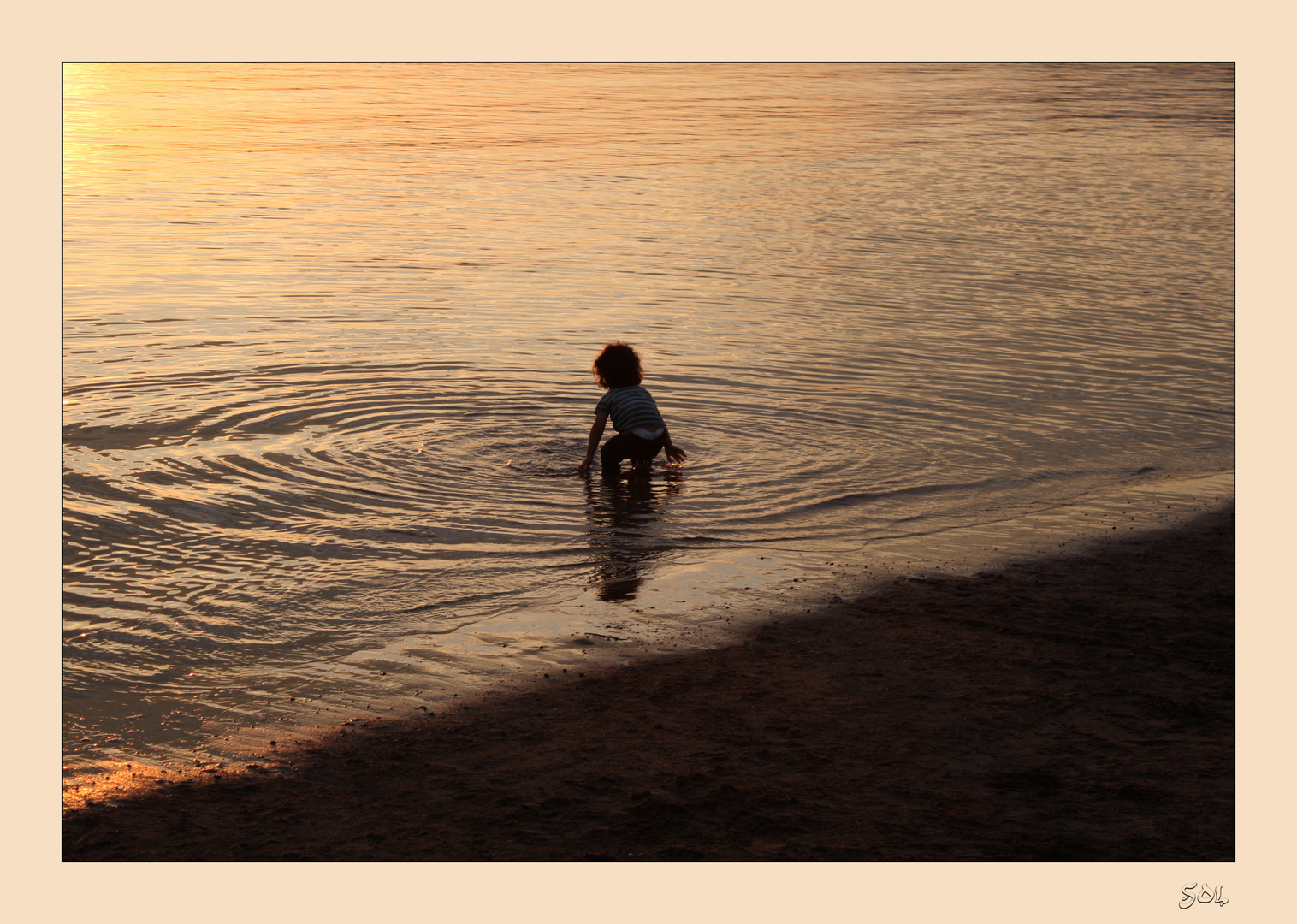 Círculos concéntricos de niño jugando en el agua al caer el sol.