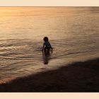 Círculos concéntricos de niño jugando en el agua al caer el sol.