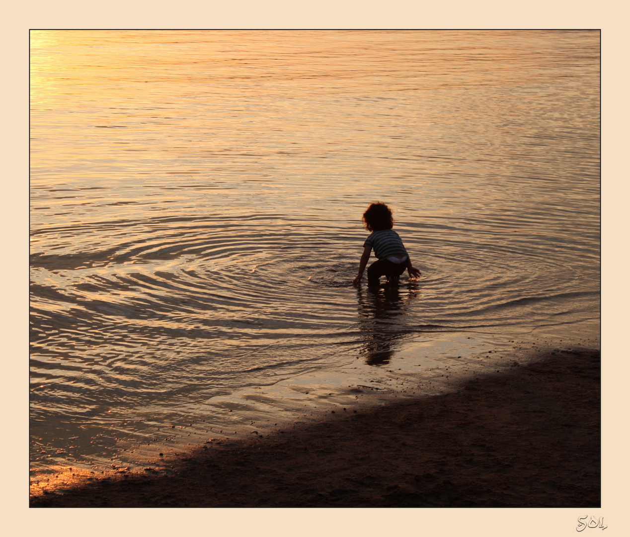 Círculos concéntricos de niño jugando en el agua al caer el sol-