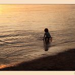 Círculos concéntricos de niño jugando en el agua al caer el sol-