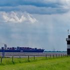 Containerschiff mit Leuchtturm "Kleiner Preuße" in Wremen im Vordergrund.