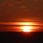 Containerschiff trifft auf untergehende Sonne