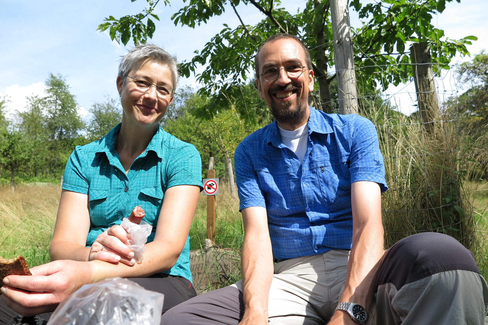 Couple of happy hikers having a picnic in a fruit orchard in the Odenwald hills