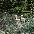 Da stehen zwei Stühle im Wald