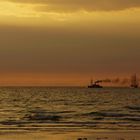 Dampfschiffe und ein Segelschiff in der Abendsonne