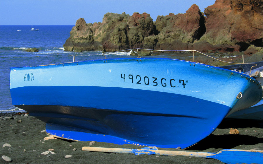 Das blaue Boot am schwarzen Strand