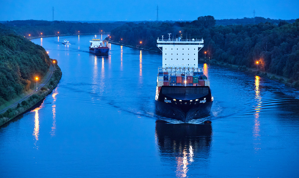 Das Containerschiff Barmbek auf dem Nord-Ostsee-Kanal zur blauen Stunde