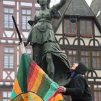 Demo Krise Frankfurt - Mann bringt Fahne an der Brunnenfigur an