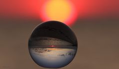 der Blick auf den Sonnenaufgang vor Westerheide auf Sylt durch die Glaskugel 