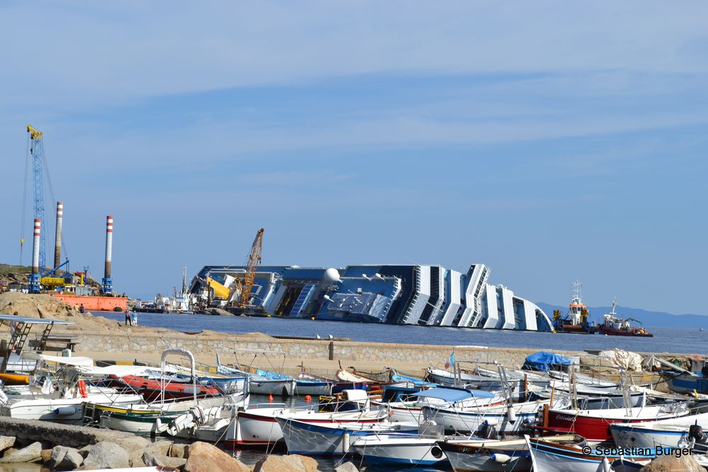 Der Jachthafen auf Giglio - Im Hintergrund die auf Grund gelaufene Costa Concordia