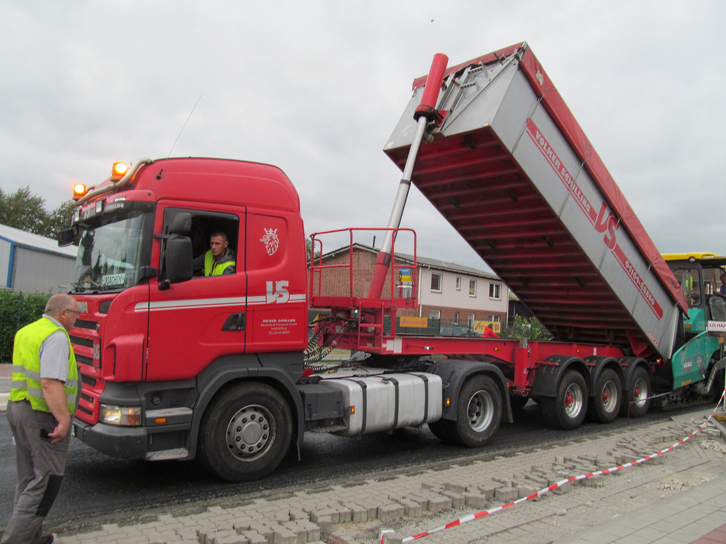 der LKW kippt den Asphalt in die Maschine ..........