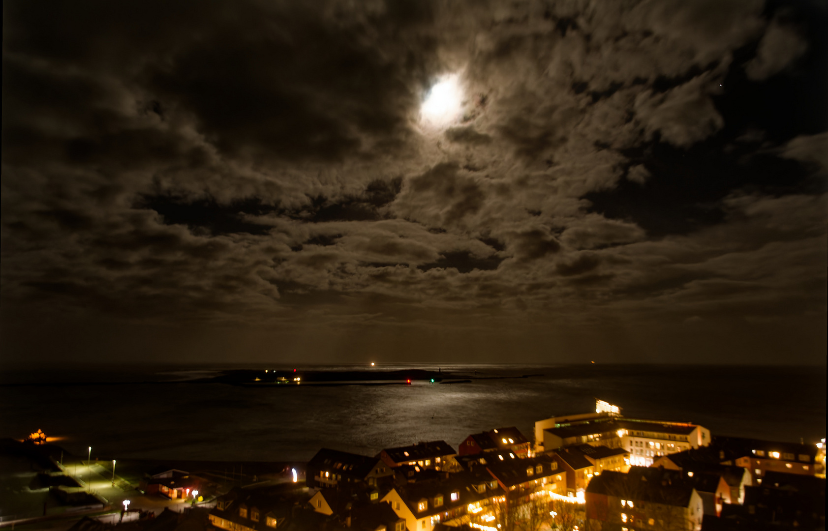 Der Mond hinter Wolken über Helgoland bei Nacht.