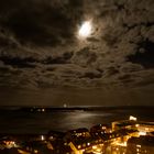 Der Mond hinter Wolken über Helgoland bei Nacht.