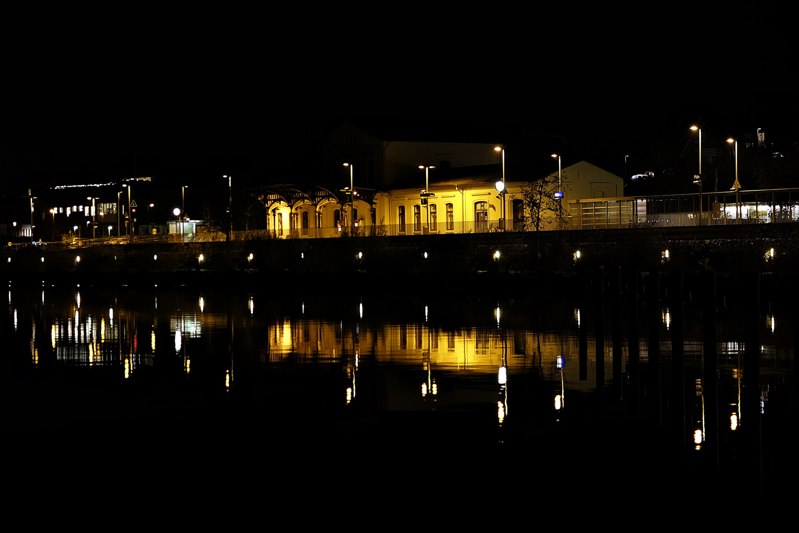 Der Plöner Bahnhof spiegelt sich nachts im Großen Plöner See