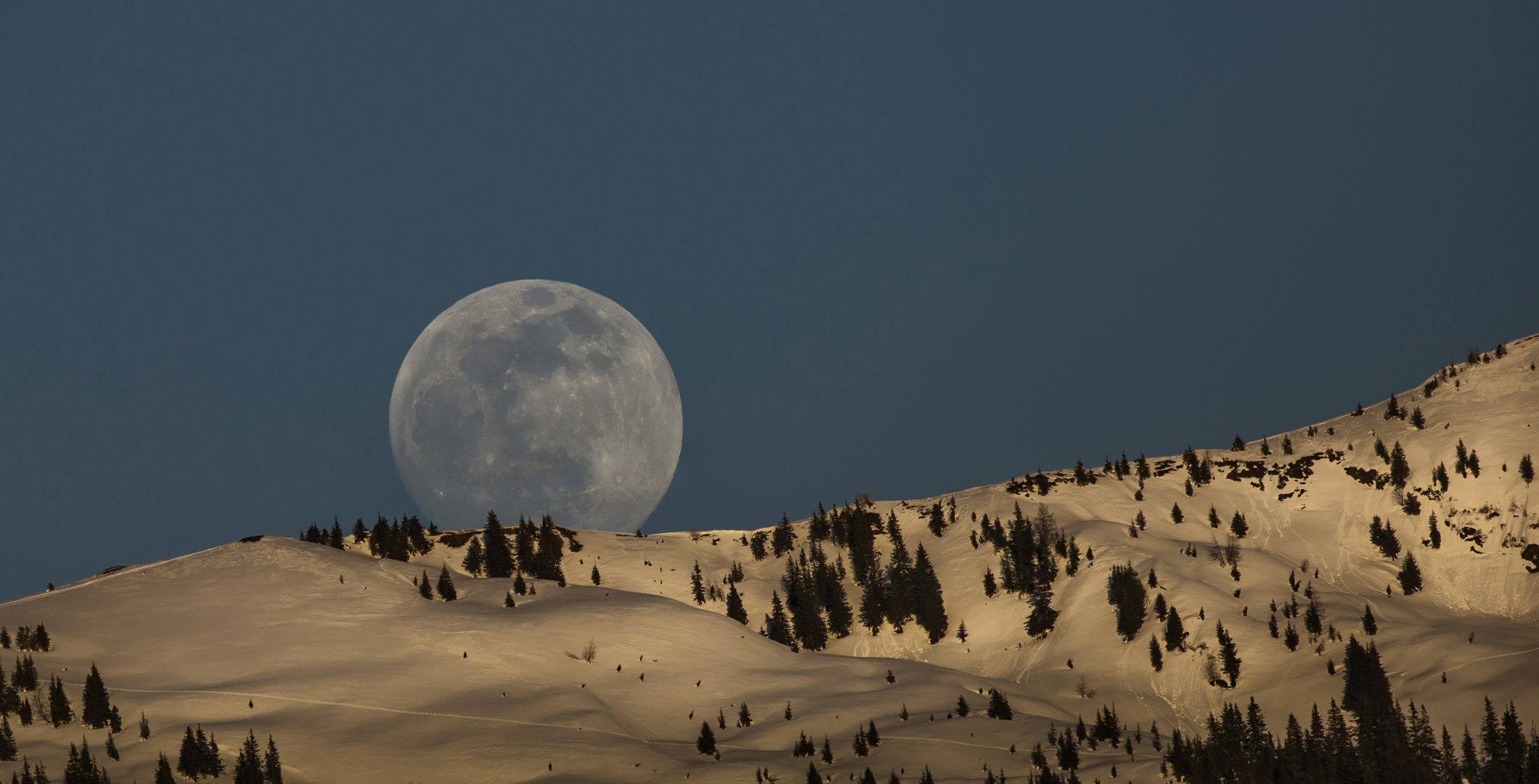 Der Vollmond geht über verschneiten Grad auf.