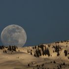 Der Vollmond geht über verschneiten Grad auf.