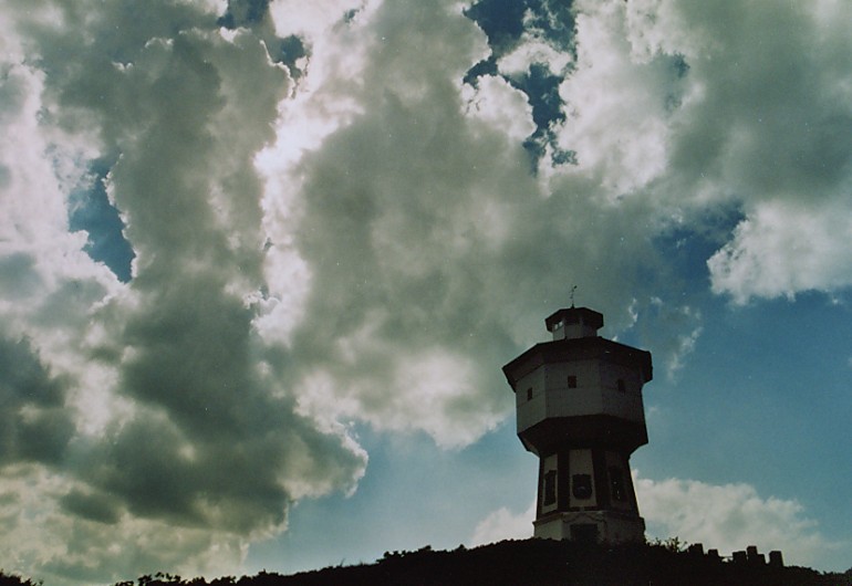 Der Wasserturm vor einem Wolken-Gebirge