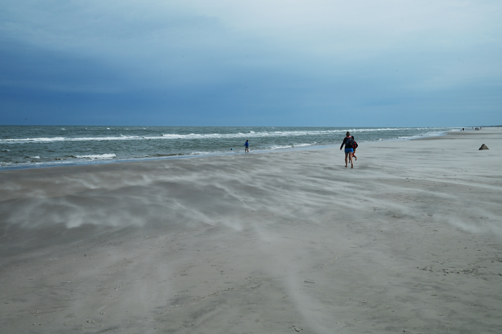 Der Wind peitscht den Sand am Strand an der Nordsee auf.