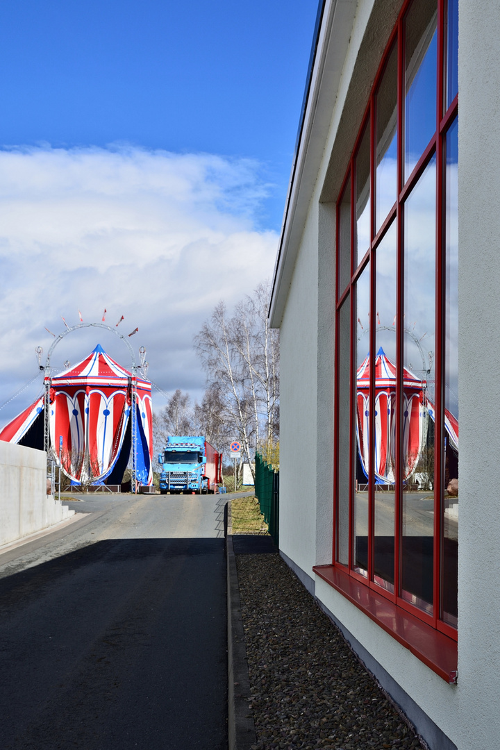 Der Zirkus spiegelt sich in den Scheiben des Gebäudes der freiwilligen Feuerwehr