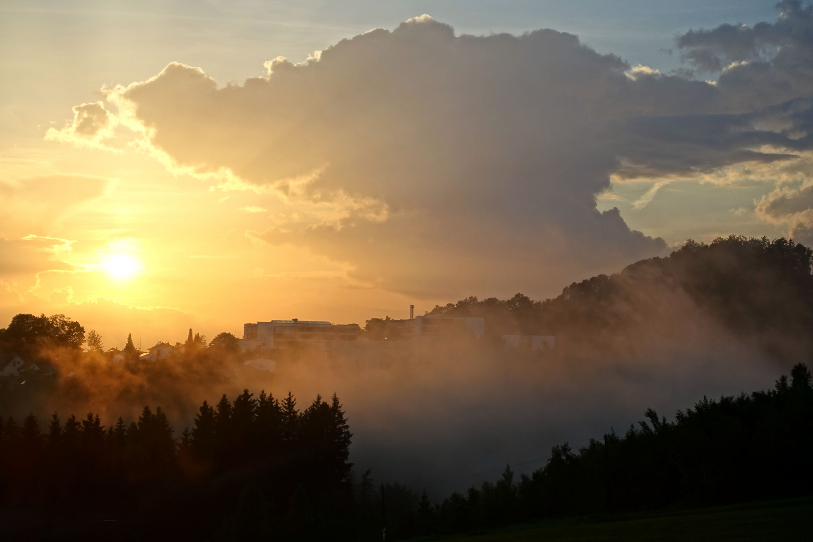 Die Abendsonne mit aufsteigenden Nebelwolken nach einem Gewitterregen.