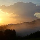 Die Abendsonne mit aufsteigenden Nebelwolken nach einem Gewitterregen.