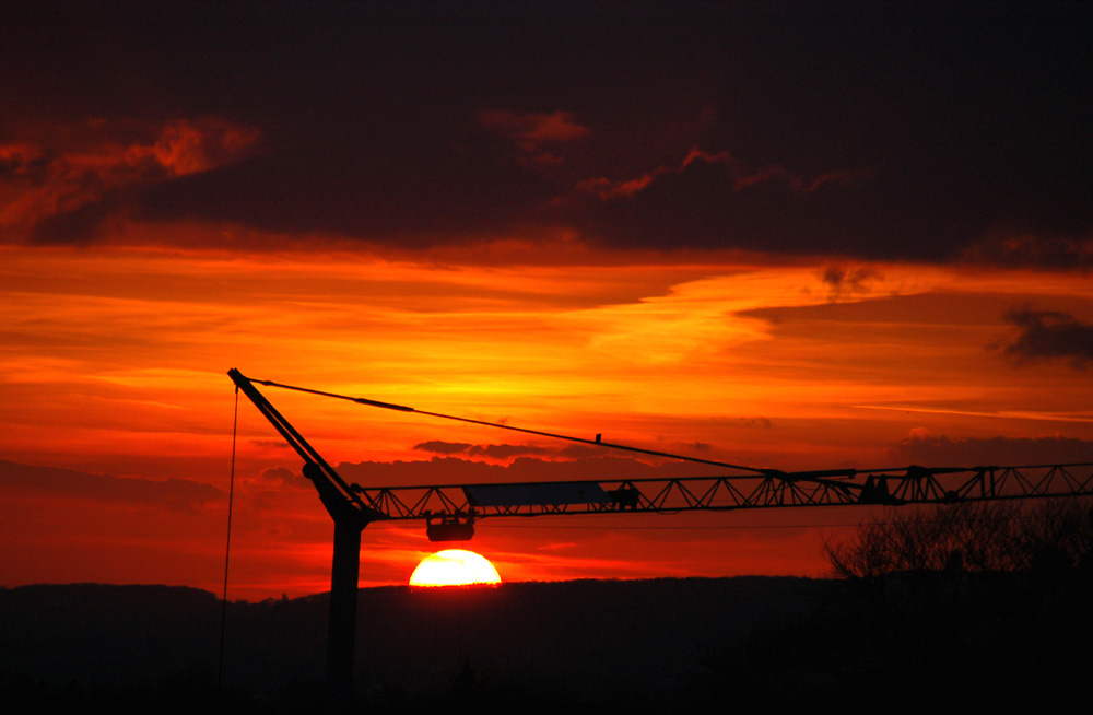 Die Abendsonne scheint am Baukran zu hängen.