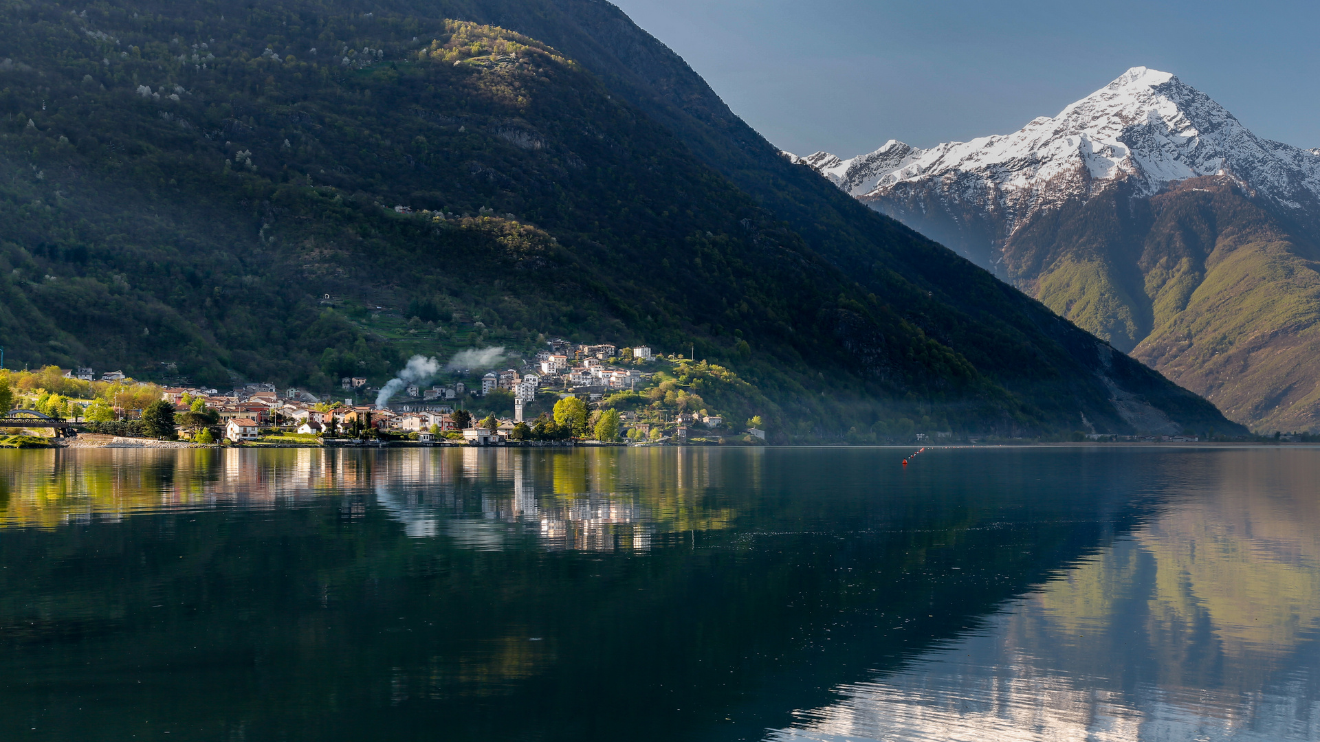 Die ersten Sonnenstrahlen erwärmen die Stadt, den See und die Berge