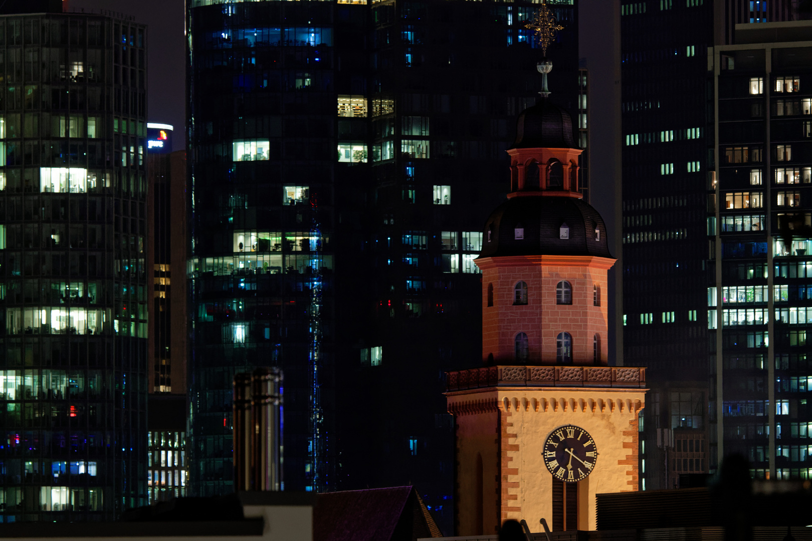 Die Frankfurter St.-Katharinen-Kirche vor einem Hochhaus-Fenster-Lichtermeer