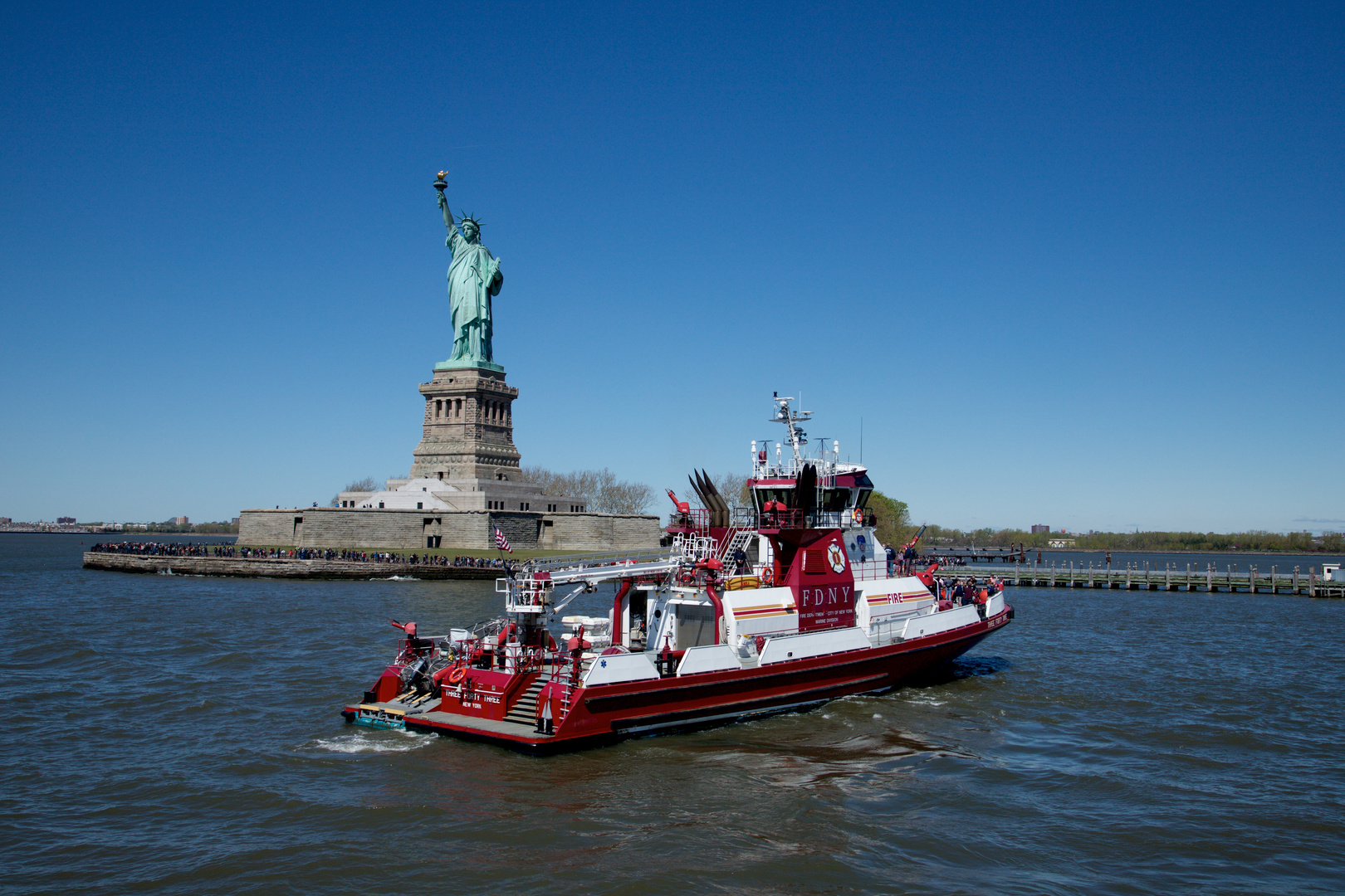 Die Freiheitsstatue von unten mit Feuerlöschboot