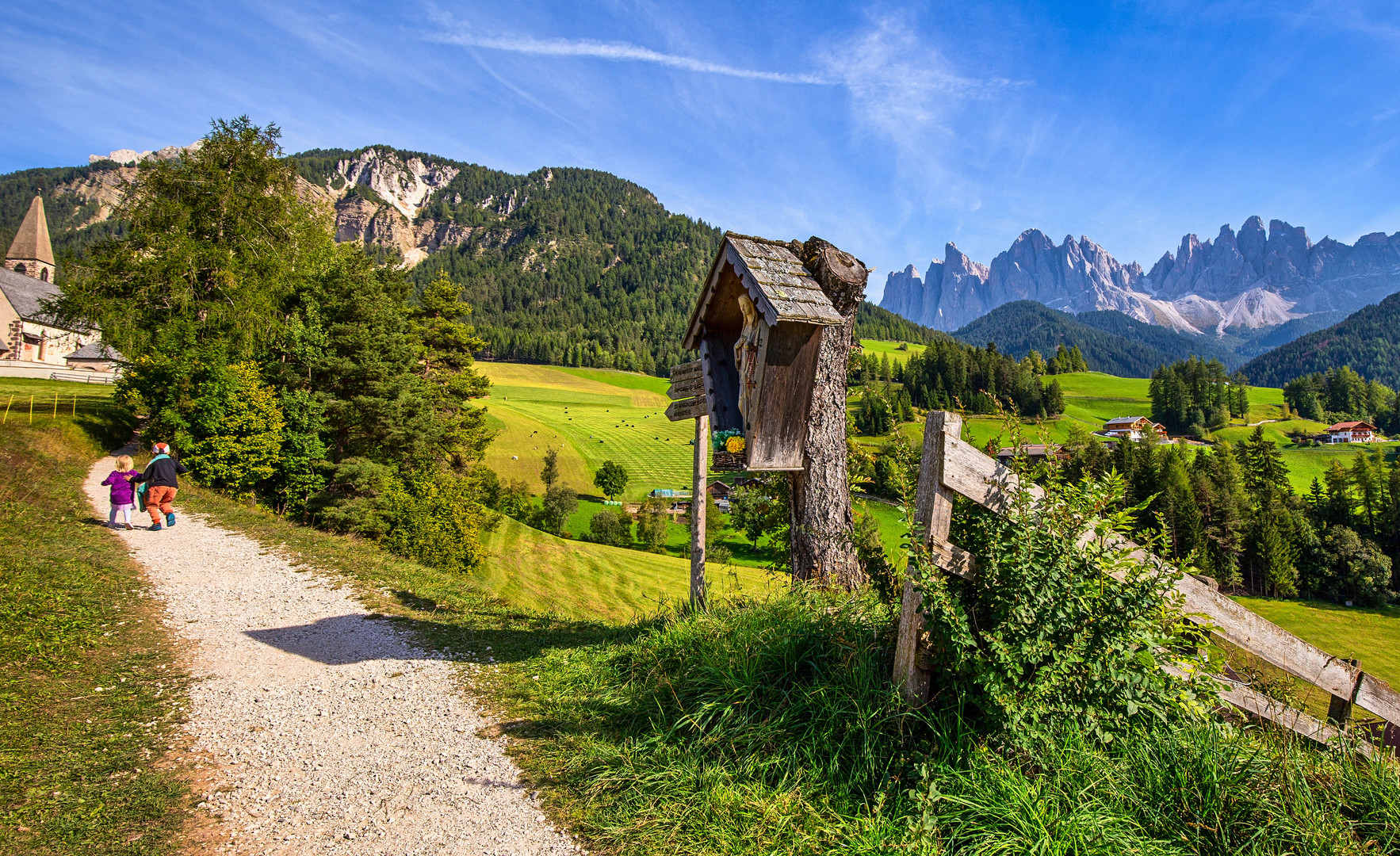 die kleine Schwester auf dem Weg zur Kirche St. Magdalena im Villnösstal anschieben