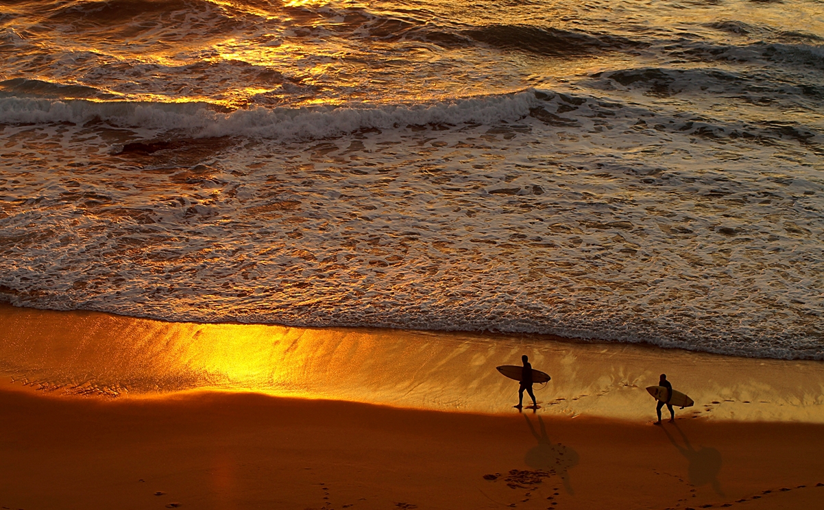 Die letzten Surfer verlassen den Strand