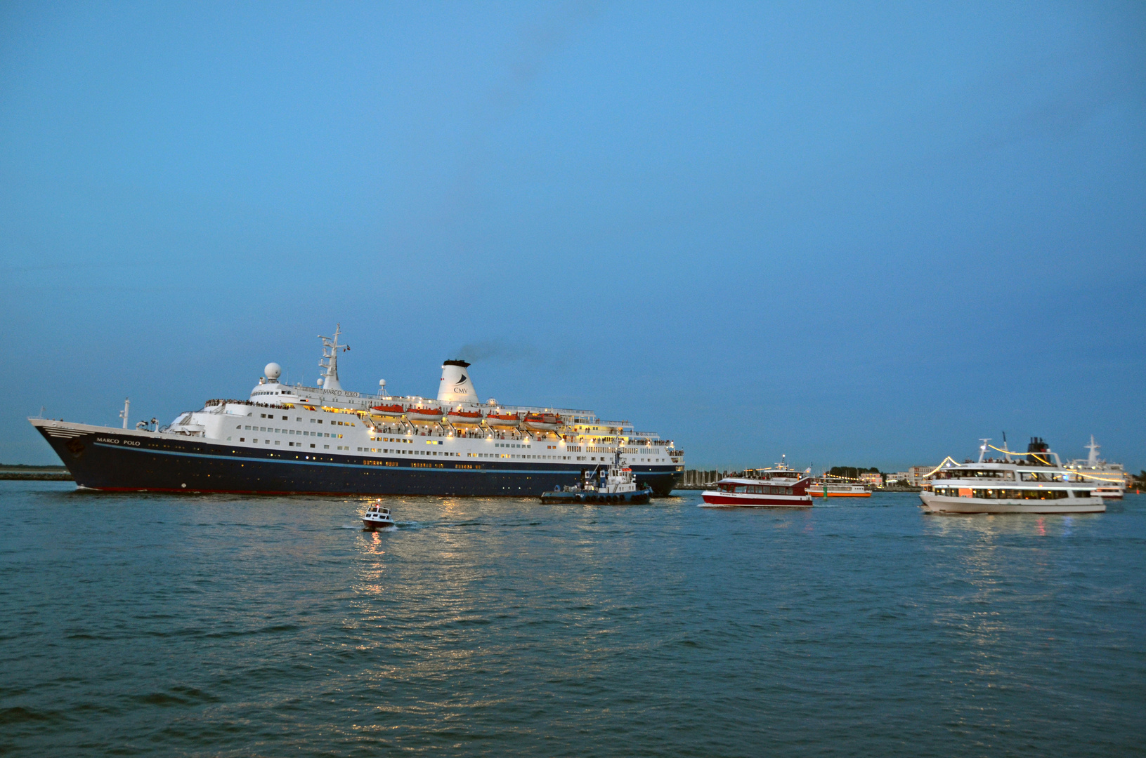 Die "Marco Polo" verlässt Warnemünde mit Fahrgastschiffen im Schlepptau
