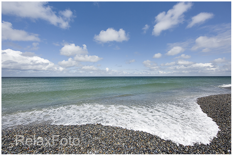 "Die perfekte Welle" - Meereswelle schwappt über Kiesstrand