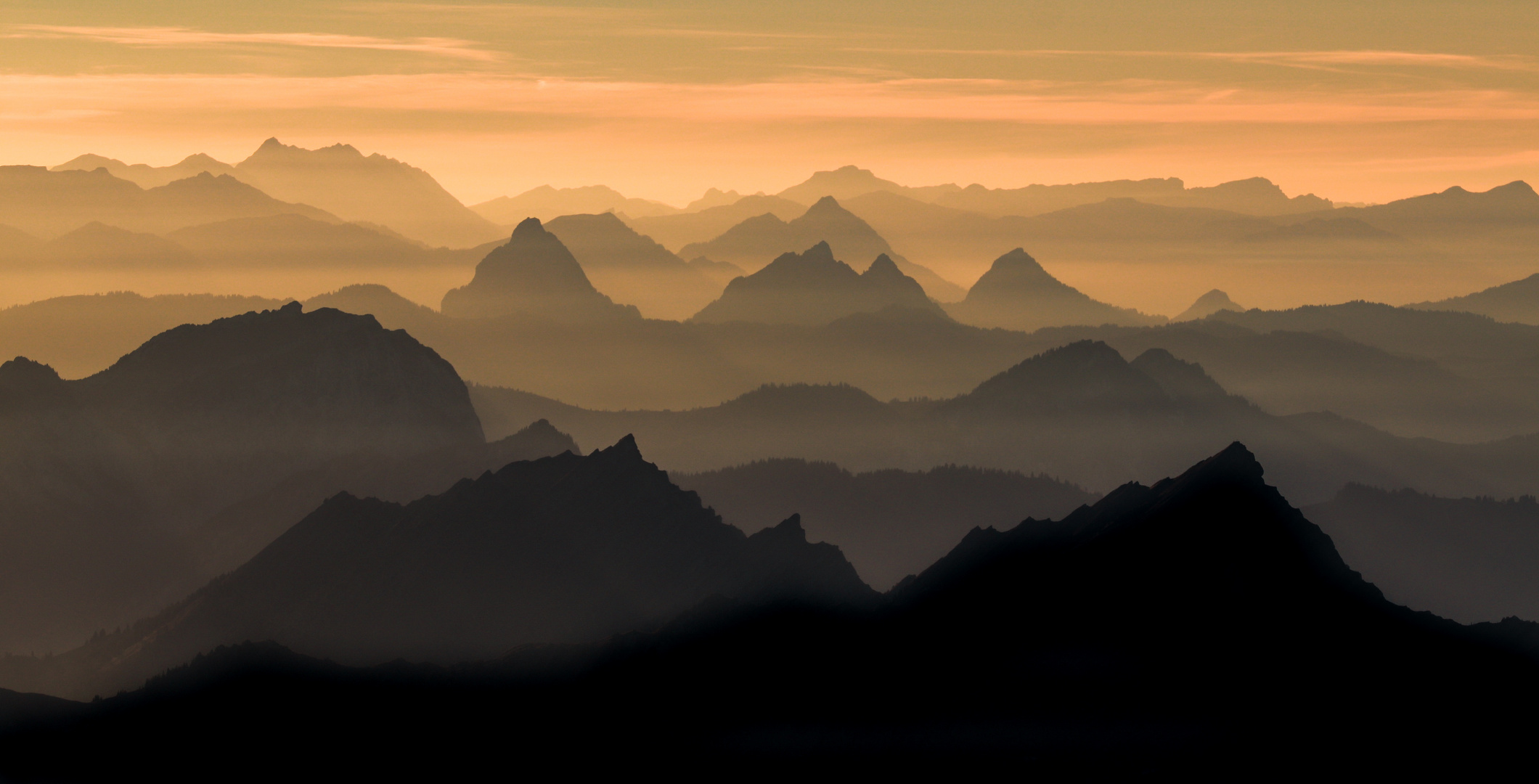 Die Schweizer Voralpen bei ockergelbem Sonnenuntergang