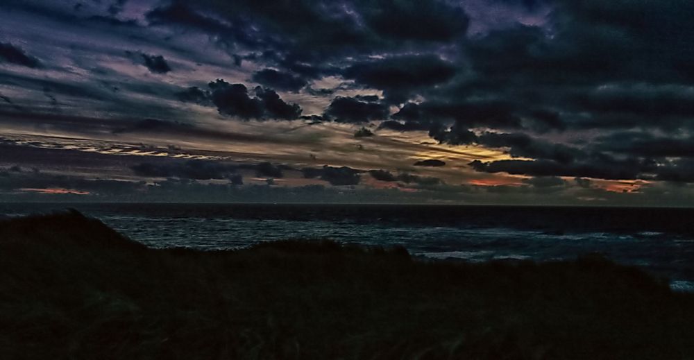 Die Sonne begibt sich hinter dunklem Wolken zur Ruhe.